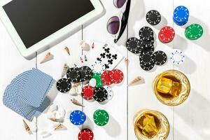 Gambling. Poker chips, cards and the dice nearby tablet on wooden table. Top view. Copyspace. Poker photo