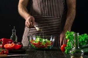 Man preparing salad with fresh vegetables on a wooden table. Cooking tasty and healthy food photo