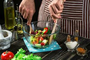 Man preparing salad with fresh vegetables on a wooden table. Cooking tasty and healthy food photo