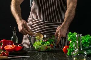 Man preparing salad with fresh vegetables on a wooden table. Cooking tasty and healthy food photo