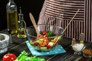 Man preparing salad with fresh vegetables on a wooden table. Cooking tasty and healthy food photo