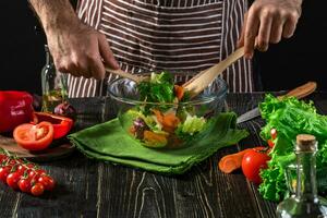 Man preparing salad with fresh vegetables on a wooden table. Cooking tasty and healthy food photo