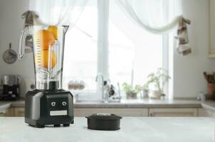 Blender and orange on wooden table in kitchen photo