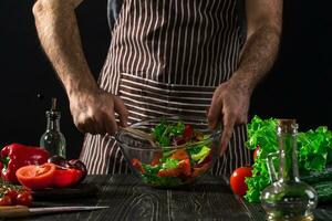 Man preparing salad with fresh vegetables on a wooden table. Cooking tasty and healthy food photo