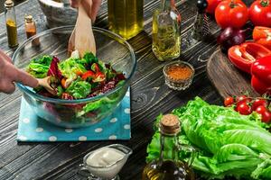 Man preparing salad with fresh vegetables on a wooden table. Cooking tasty and healthy food. Close-up photo