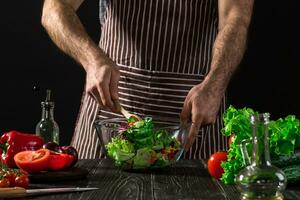 Man preparing salad with fresh vegetables on a wooden table. Cooking tasty and healthy food photo