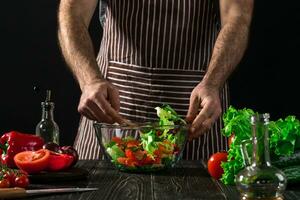 Man preparing salad with fresh vegetables on a wooden table. Cooking tasty and healthy food photo