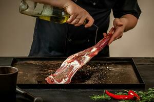 Male chef pouring lamb shank with oil. Chef cooking appetizing shank of lamb. photo