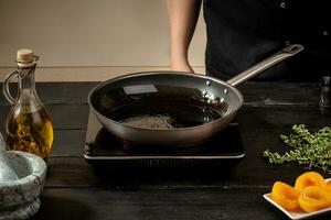 Top view of frying pan with olive oil on wooden table. photo