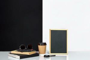 Blank blackboard and books on table near white and black wall. photo