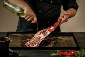 Male chef pouring lamb shank with oil. Chef cooking appetizing shank of lamb. photo