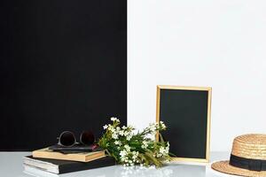 Blank blackboard and books on table near white and black wall. photo