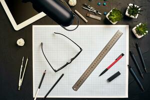 Top view of the builder's workplace, ruler, paper for drawings, compasses, glasses, tablet photo