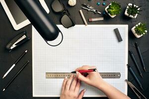 Office desk background hand with pen writing construction project ideas concept, With tablet, drawing equipment and lamp. View from above photo