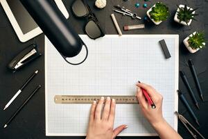 Office desk background hand with pen writing construction project ideas concept, With tablet, drawing equipment and lamp. View from above photo