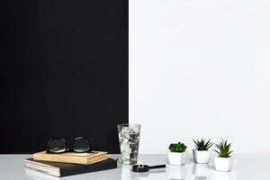 Book, notebook, glasses and a glass of water, black and white wall. photo