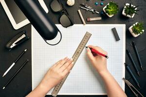 Office desk background hand with pen writing construction project ideas concept, With tablet, drawing equipment and lamp. View from above photo