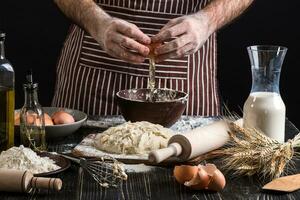 Cook accurately breaks the egg to make dough. photo