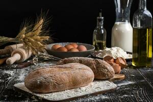 Beautiful still life with different kinds of bread, grain, flour on weight, ears of wheat, pitcher of milk and eggs photo