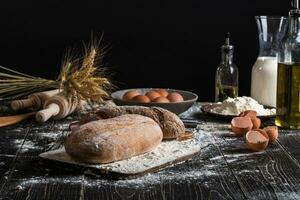 Beautiful still life with different kinds of bread, grain, flour on weight, ears of wheat, pitcher of milk and eggs photo