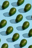 Colorful fruit pattern of fresh whole avocado arranged on blue pastel background photo