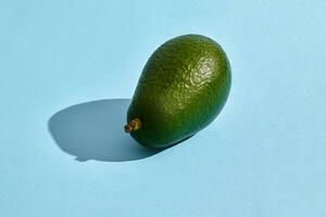 Close up high quality image of whole avocado, fruit composition on blue pastel photo