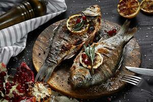 Grilled carp with lemon on wooden board, horizontal view from above close-up photo