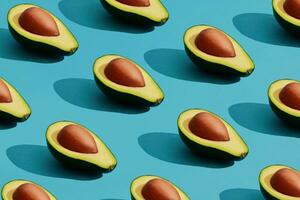 Colorful fruit pattern of fresh cutted avocado halves with pits on blue pastel background photo