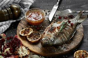 Grilled carp with lemon on wooden board, horizontal view from above close-up photo