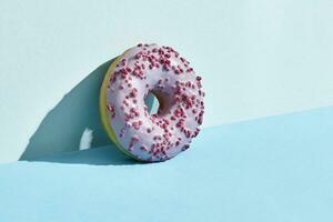 Food design. Close up high quality image of pink glazed donut on blue background photo