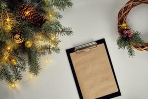 Flat lay of juniper wreath green pine tree branches, wreath and craft paper on white table, top view. photo