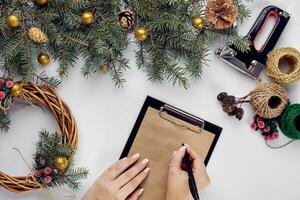 Creative christmas diy. Woman making handmade xmas wreath. Home leisure, tools, trinkets and details for holiday decorations on white table background. Top view photo