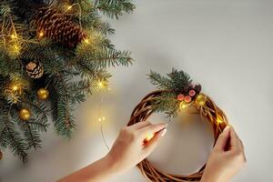 Top view of female hands make a Christmas wreath. Packed gifts and scrolls, spruce branches and tools on white table. photo