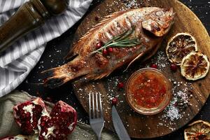 Grilled red mullet on a wooden board with lemon and garnet. Healthy eating concept photo