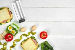 Lunch. Sandwiches and fresh vegetables, bottle of water and green apple on wooden table. Healthy eating concept. Top view photo