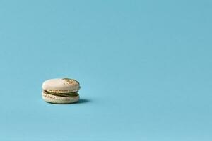 One cake of macaroni white color. Delicious caramel macaroon on blue background. French sweet cookie photo