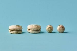 White macarons cake with colorful powder, top view, flat lay, sweet macaroon on blue background. Different size cookies photo