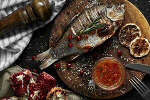 Grilled carp with lemon on wooden board, horizontal view from above close-up photo