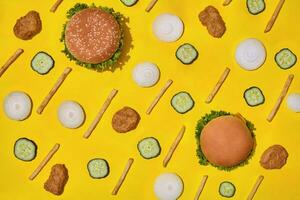 Most popular fast food meal. Chicken nuggets, burgers and french fries on yellow background top view photo