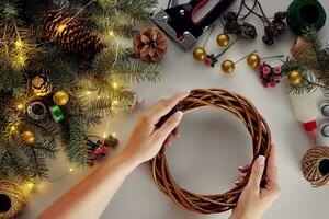 hembra manos Decorar el Navidad guirnalda con abeto ramas con un rojo baya y bosque conos blanco antecedentes. nuevo años concepto. foto