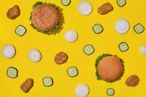 Most popular fast food meal. Chicken nuggets, burgers with fresh cucumber and onions on yellow background top view photo