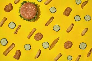 Most popular fast food meal. Chicken nuggets, burger and french fries on yellow background top view photo