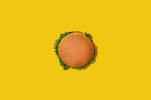 Tasty fresh unhealthy hamburger with ketchup and vegetables on yellow vibrant bright background. Top View with Copy Space. photo