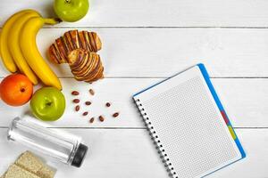 Planning concept. Fruits, croissants and notebook on white wooden background. Space for a text. Top view. photo