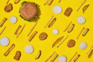 Most popular fast food meal. Chicken nuggets, burger and french fries on yellow background top view photo