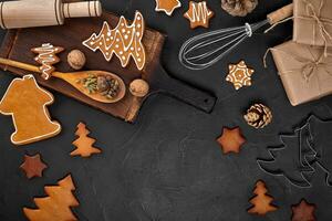 Christmas homemade gingerbread cookies, spices and cutting board on dark background with copy space for text top view. New year and christmas postcard photo