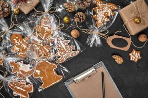 A Christmas gingerbread cookie in the shape of a Christmas tree in a cellophane packing on the background of a dark table. Christmas gift concept. photo