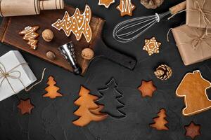 Christmas homemade gingerbread cookies, spices and cutting board on dark background with copy space for text top view. New year and christmas postcard photo