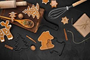 Christmas homemade gingerbread cookies, spices and cutting board on dark background with copy space for text top view. New year and christmas postcard photo