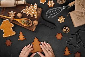 mujer decorando pan de jengibre Navidad galletas con Formación de hielo azúcar. Navidad preparativos concepto. parte superior ver con Copiar espacio. foto